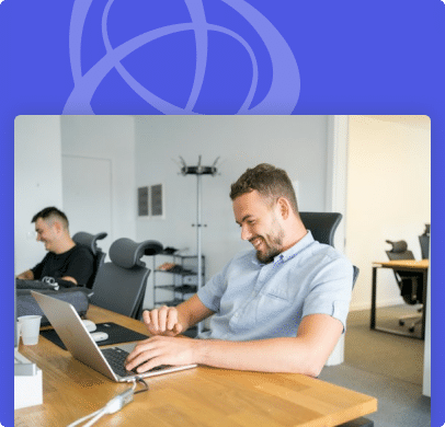 Hommes souriants travaillant sur des ordinateurs portables dans un bureau moderne.