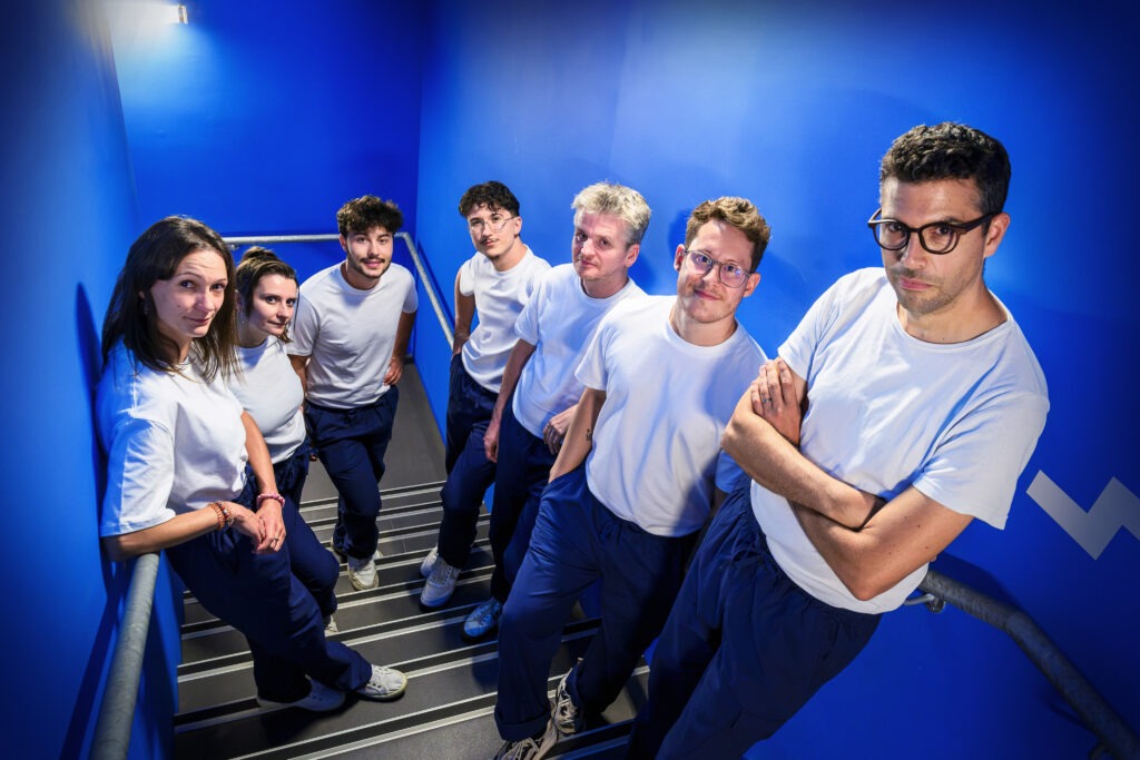 L'agence : une équipe souriante sur des escaliers bleus