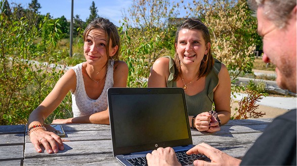 Trois personnes discutent devant un ordinateur portable lors d'une réunion d'agence.